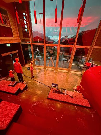 Cleaning a full-height atrium window in the evening.
