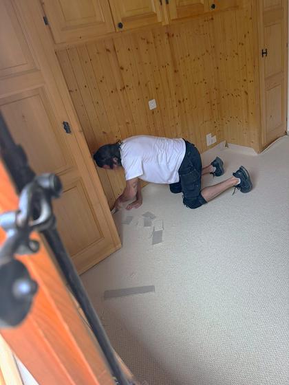 Fitting carpet gripper along the edge of a chalet bedroom.