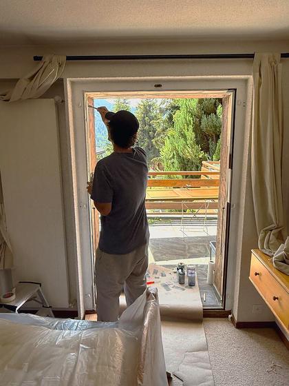 Painting a door frame inside a chalet bedroom.