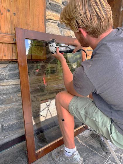 Sanding a window frame back before refinishing.