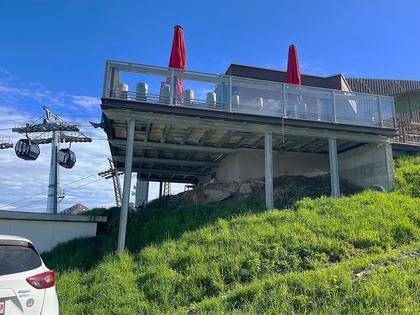 A mountain restaurant terrace with glass balustrades above the gondola line.